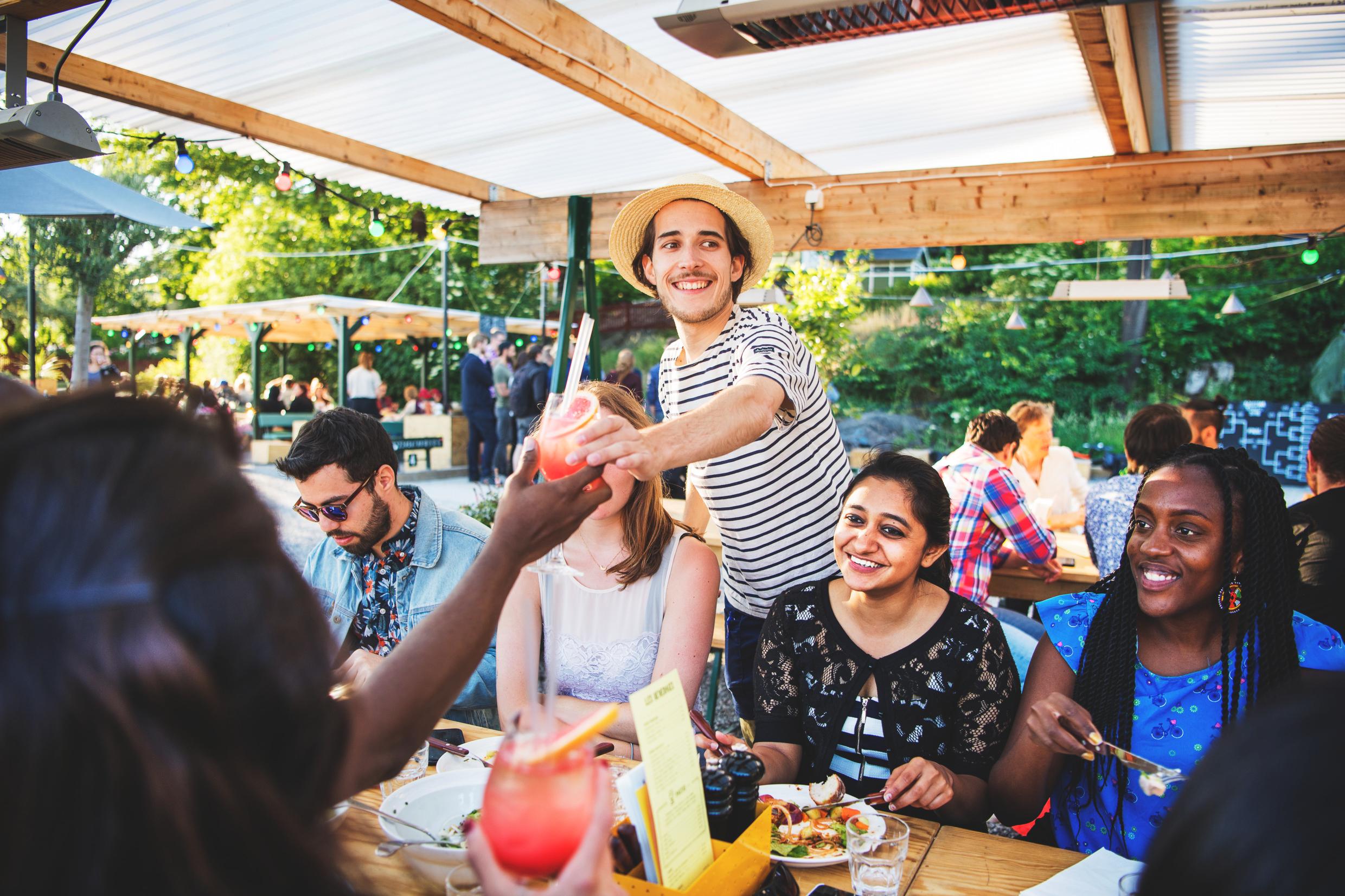 A crowded outdoor restaurant with people eating and drinking.