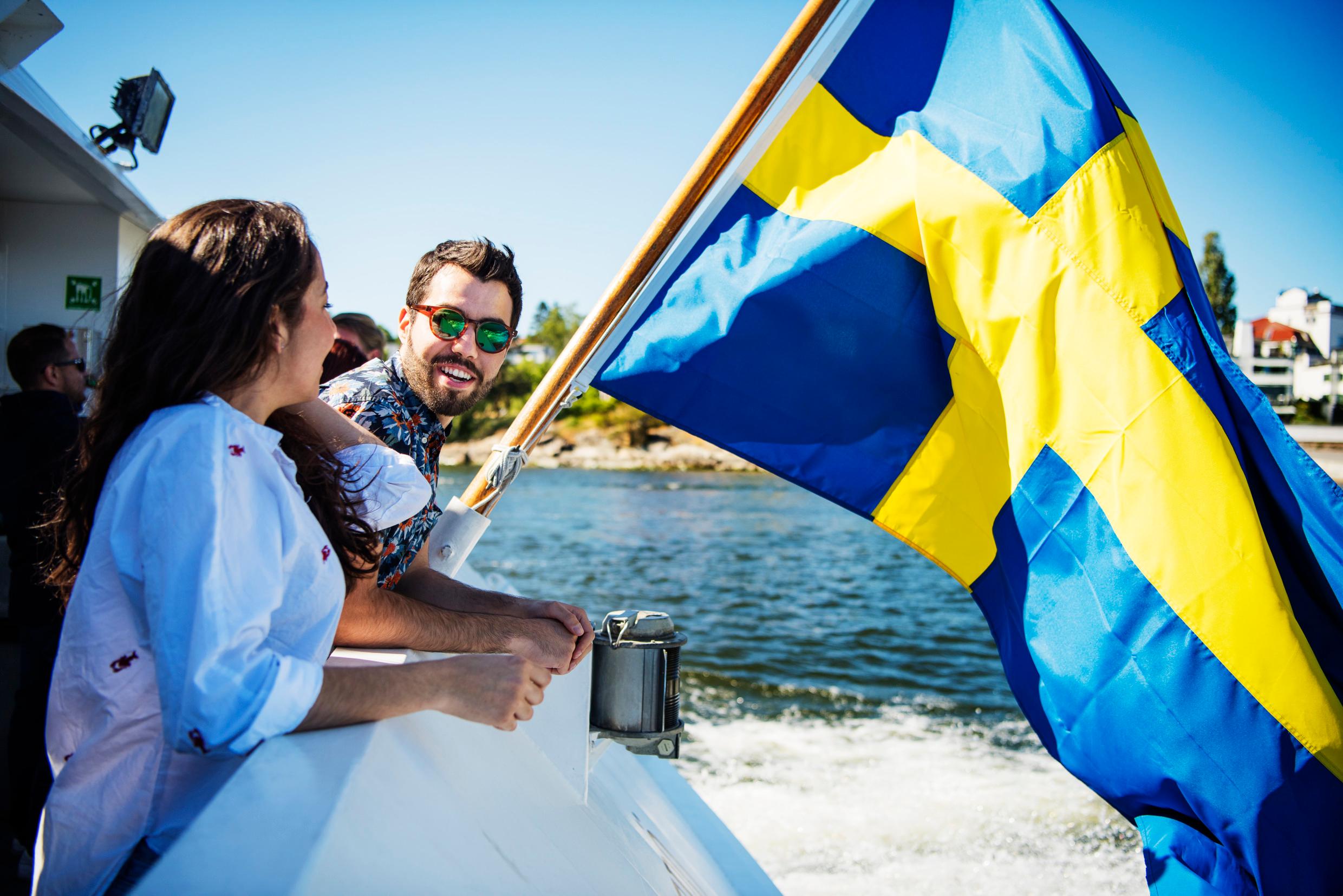 أصدقاء يتحدثون بجوار نهر وترى علم السويد