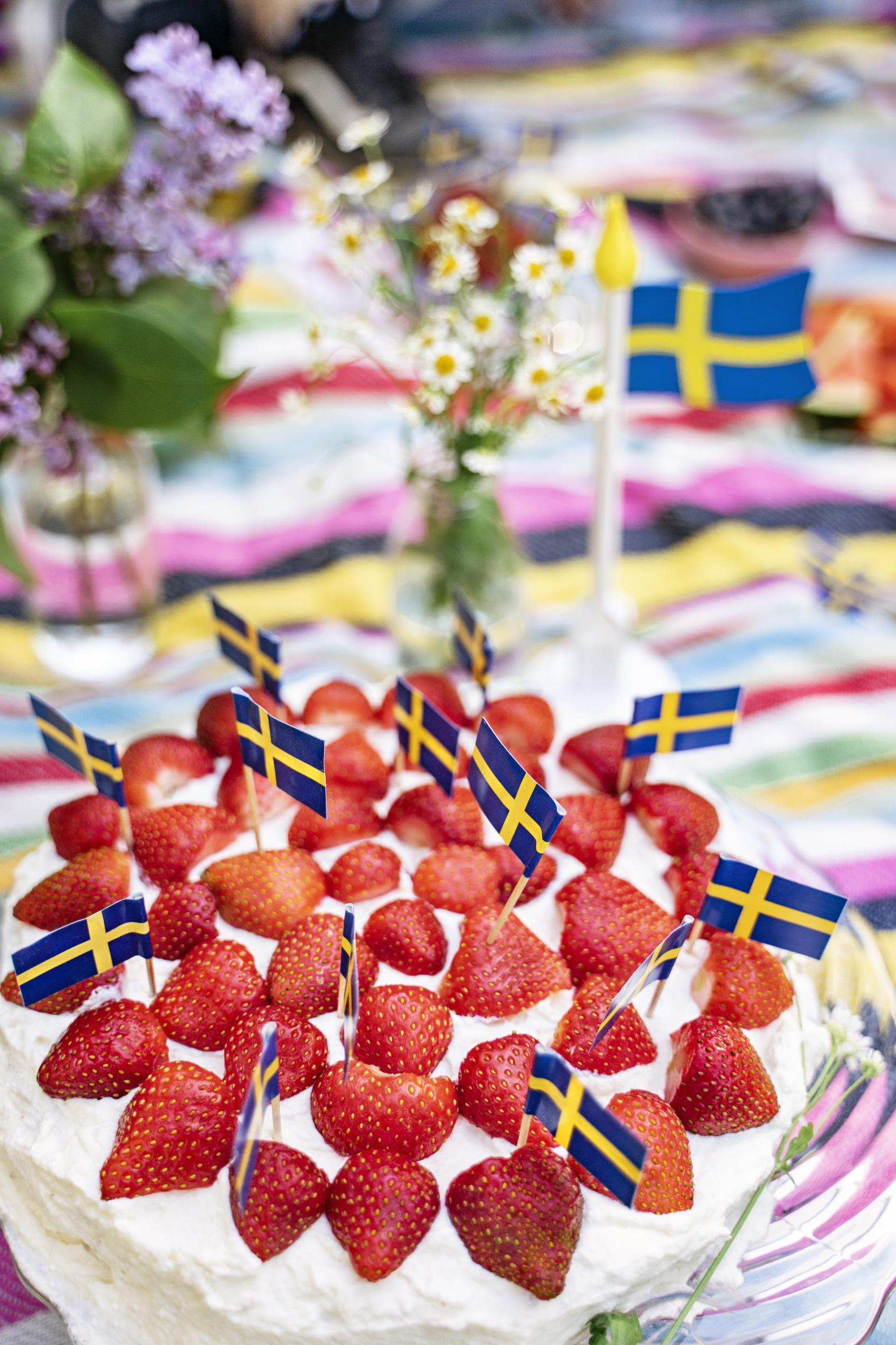 كعكة فراولة مزينة بالعديد من الأعلام السويدية الصغيرة.