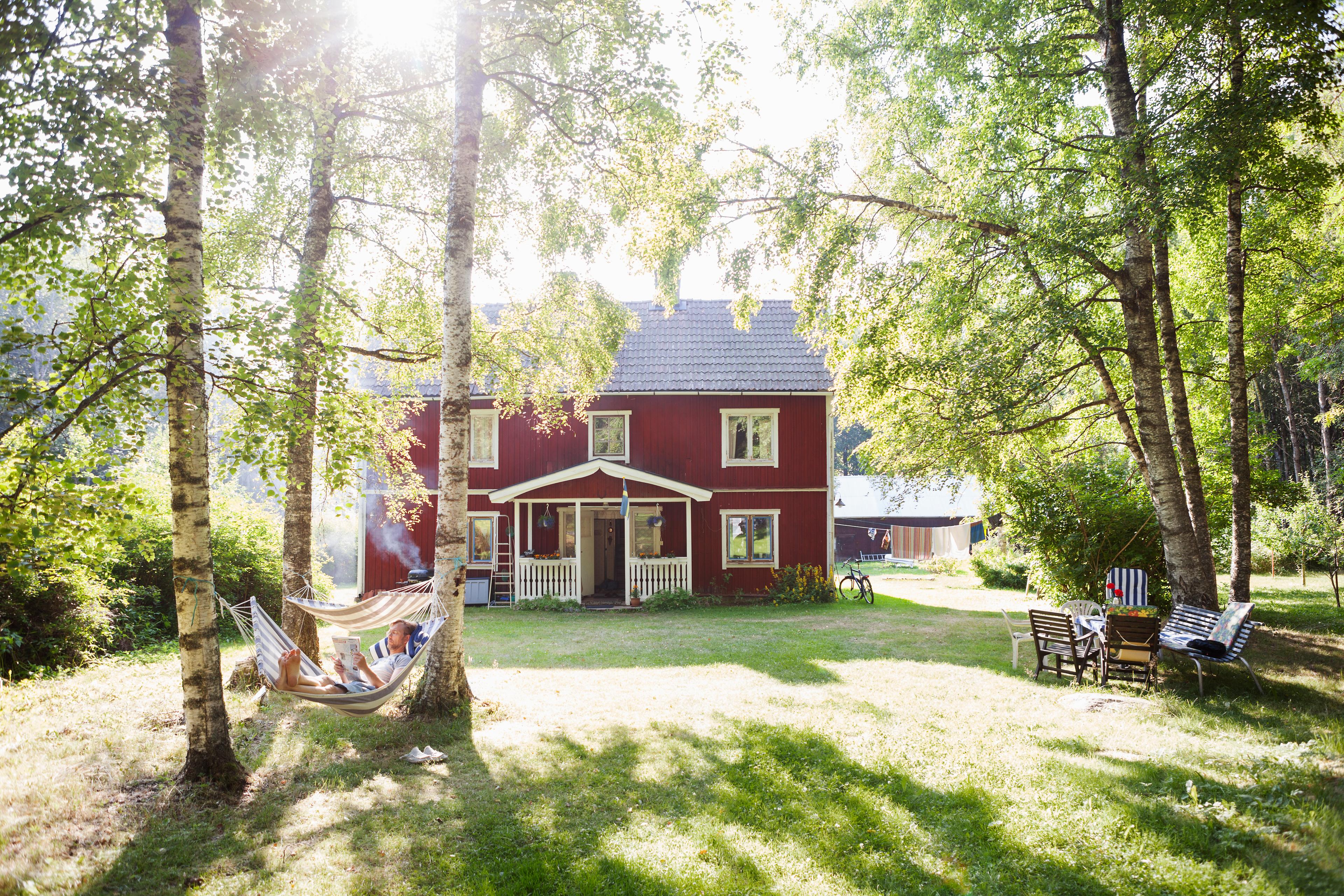 منزل سويدي تقليدي أحمر اللون بها مساحات خضراء وأشجار وأراجيح وأثاث حدائق.