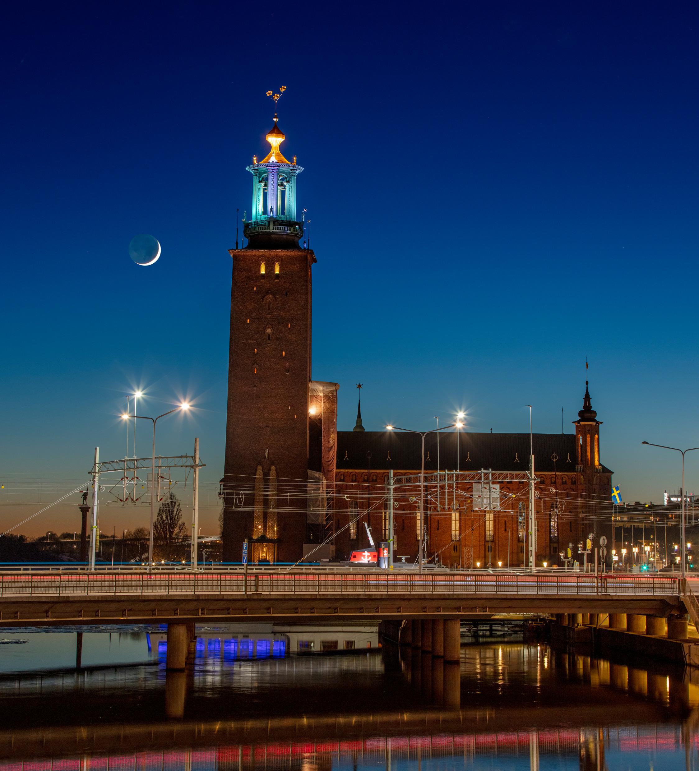 يضيء القمر الجديد خلف مبنى بلدية ستوكهولم.