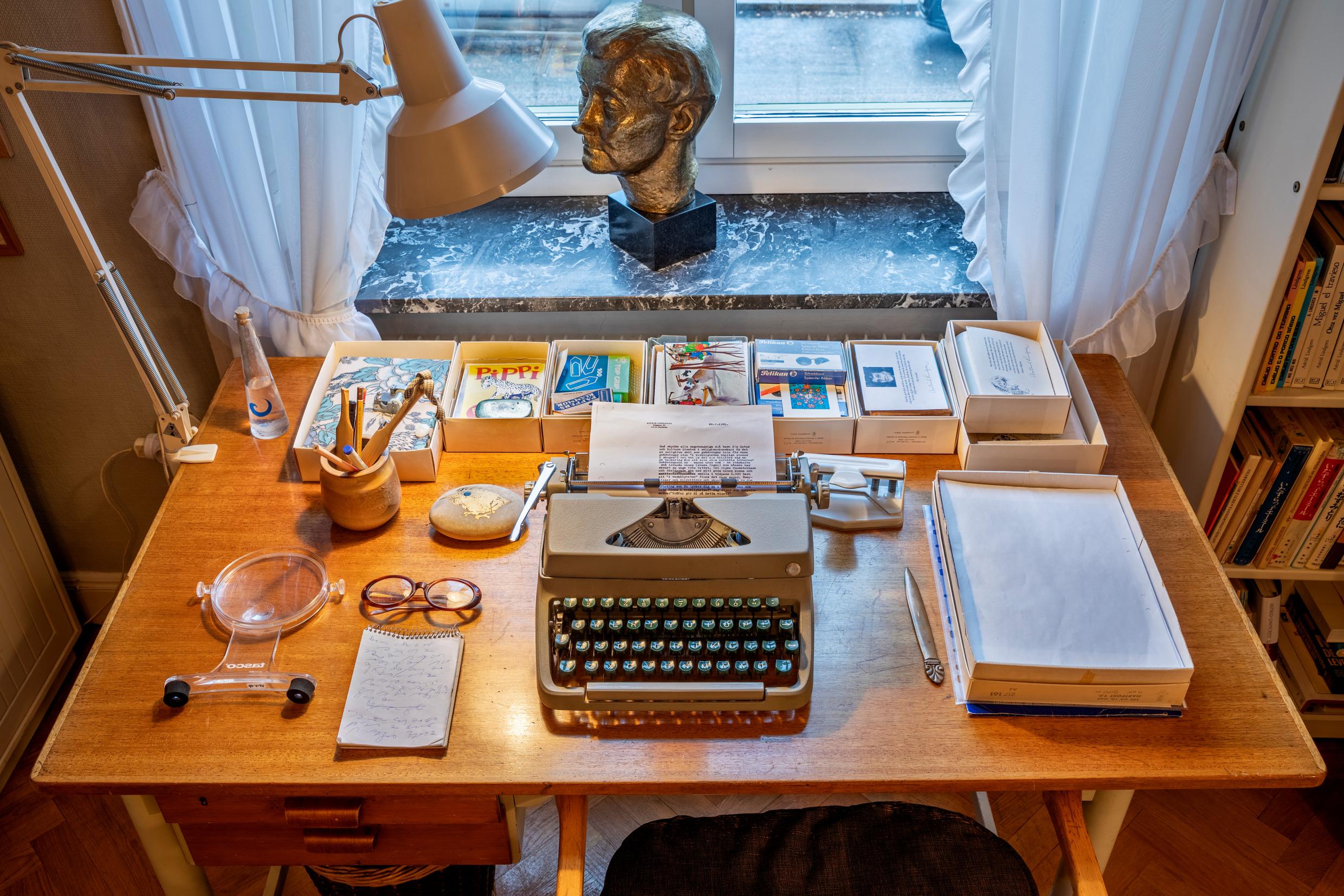 مكتب به مصباح للقراءة وآلة كاتبة وكتب وأشياء أخرى.