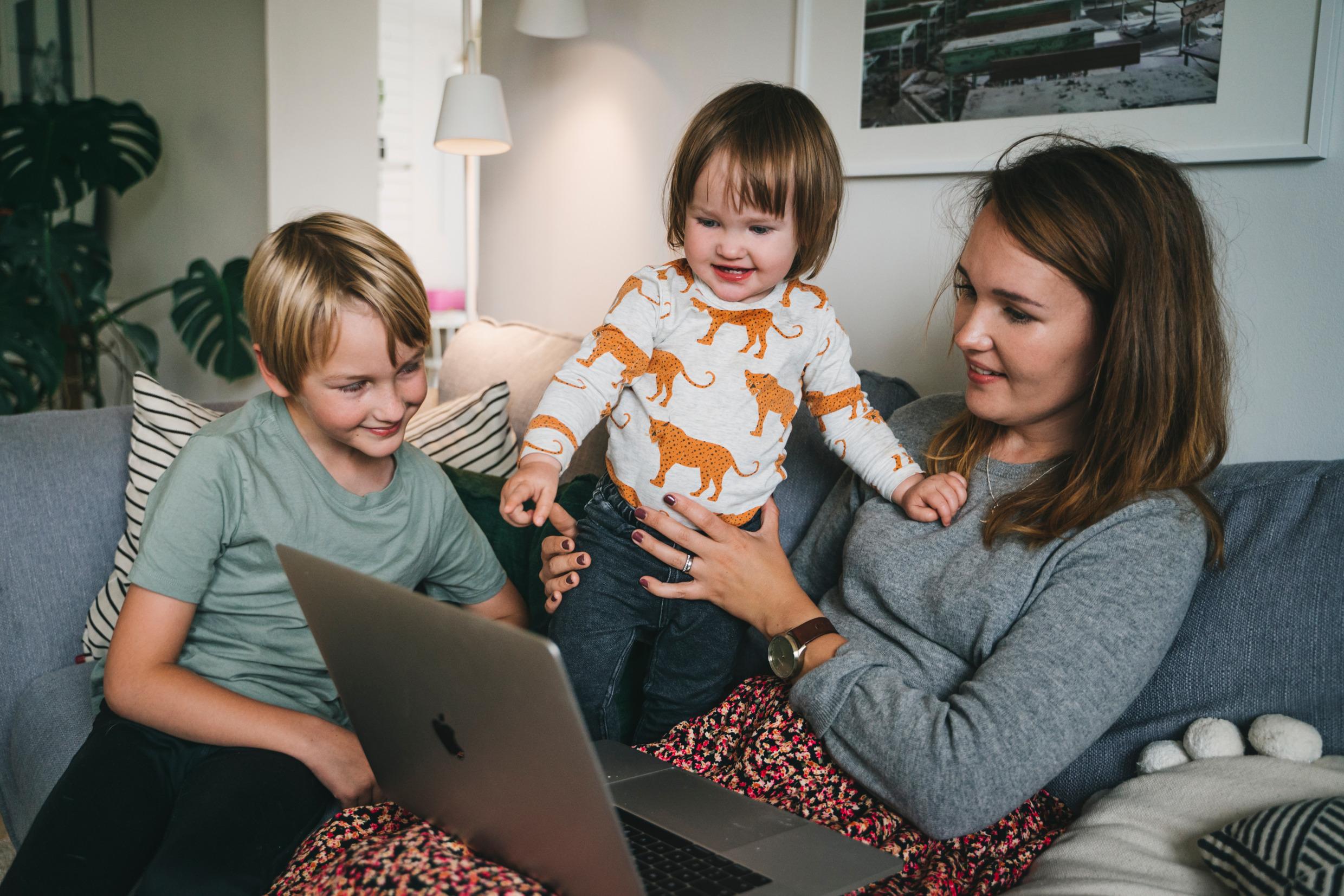 أم وأطفال ينظرون إلى شاشة كمبيوتر محمول.
