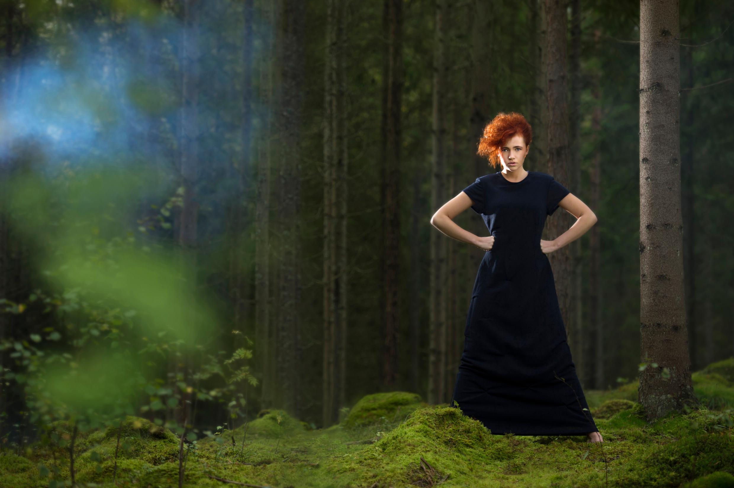 عارضة أزياء تقف في غابة خضراء