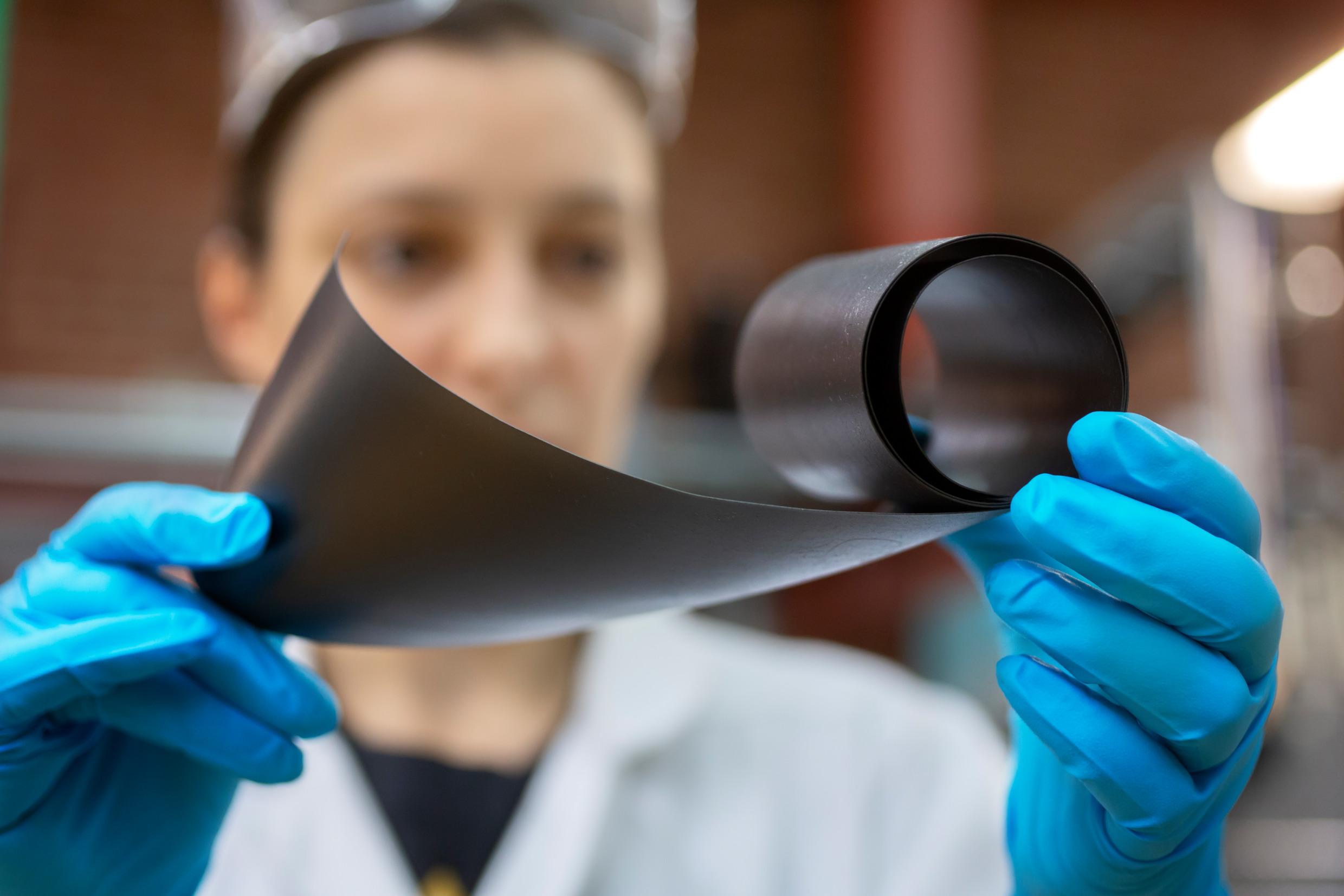 A woman holding up a roll of graphene.